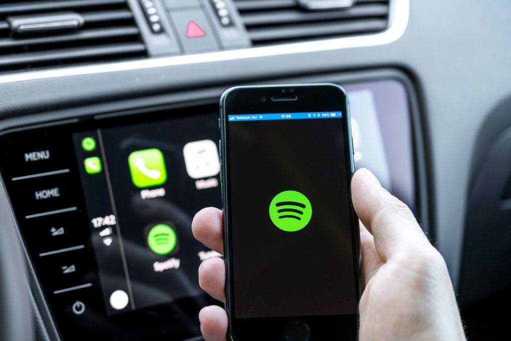 male-hands-holding-a-smartphone-that-is-connecting-to-the-cars-computer-running-the-popular-music-streaming-service